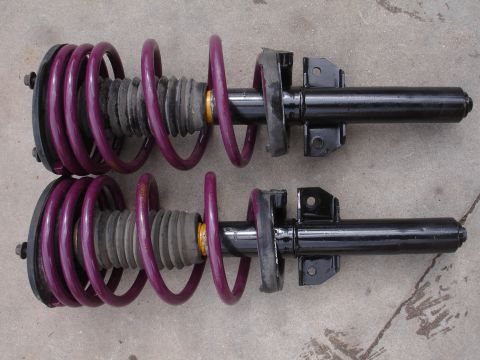1995 Ford Taurus - A pair of purple performance coilover suspension struts are displayed against a concrete surface.