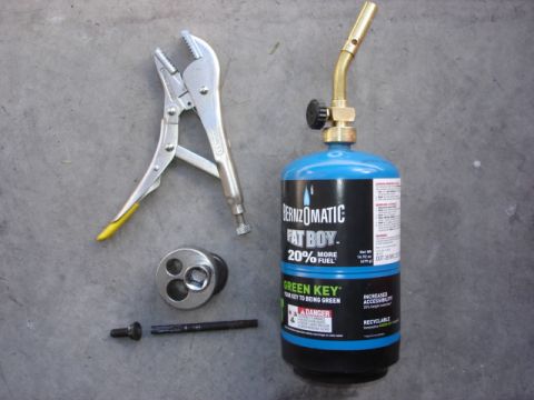 1992 Ford Bronco - A Bernzomatic Fat Boy propane torch is shown with locking pliers, a socket adapter, and a bolt on a concrete surface.