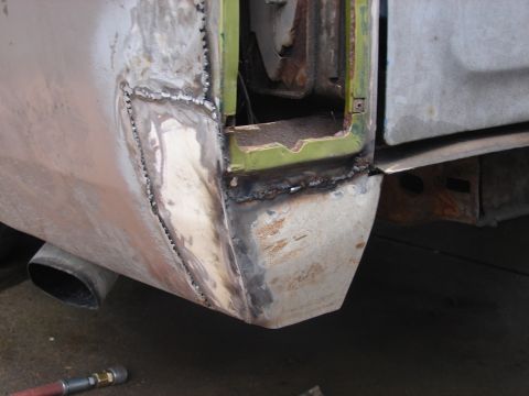 1973 Ford Ranchero - Close-up of a vehicle's rear quarter panel undergoing repair, showing extensive welding and primer application.