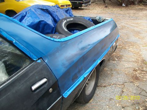 1973 Ford Ranchero - A blue Ford Ranchero is taped off and ready for bodywork, with a spare tire and tarp in the bed. Another vehicle is visible in the backgrou…