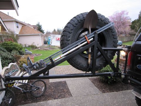 1996 Ford Bronco - Rear view of a black Ford Bronco with a spare tire carrier, hi-lift jack, shovel, and bicycle mounted.