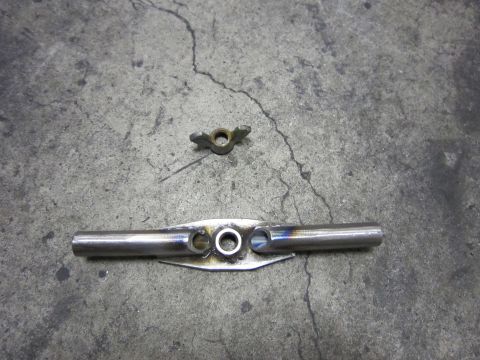 1996 Ford Bronco - A metal component with three circular openings and a separate wing nut rests on a concrete surface.