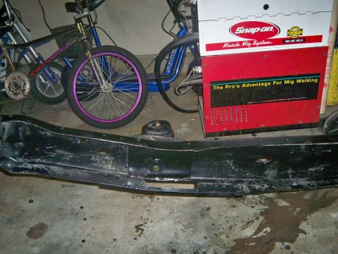 1985 Ford Bronco - A bumper lies on the floor with bicycles and a welding machine behind it.