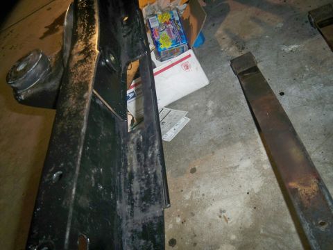 1985 Ford Bronco - A close-up view of a vehicle frame section and a rusty metal bar on a concrete floor, with boxes in the background.
