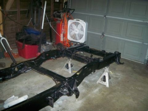 1985 Ford Bronco - The frame of a vehicle is elevated on jack stands, suggesting it is undergoing maintenance or a rebuild.