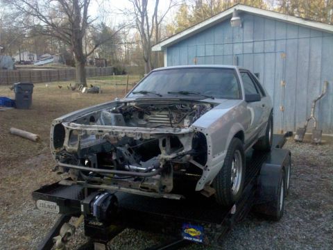 1986 Ford Mustang - This 1986 Ford Mustang is on a trailer, ready for transport or work, with its front end disassembled.