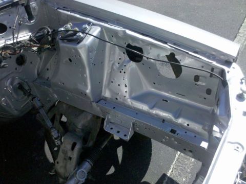 1986 Ford Mustang - The engine bay of a car is shown, stripped down and empty, revealing the internal structure.