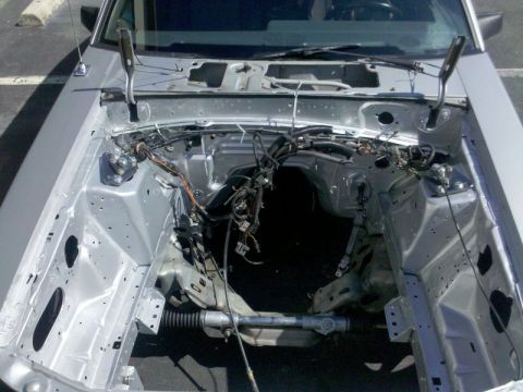 1986 Ford Mustang - Freshly painted silver Fox-body Mustang engine bay photographed from the front with the hood off and the drivetrain removed, showing bare i…