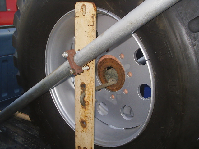 Off-road tire on a silver eight-hole wheel held by a homemade pipe-and-board rack