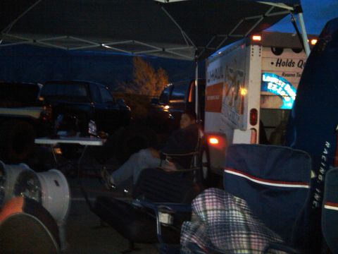 1986 Ford Bronco - Several vehicles are parked under a canopy at dusk, with a U-Haul truck visible.