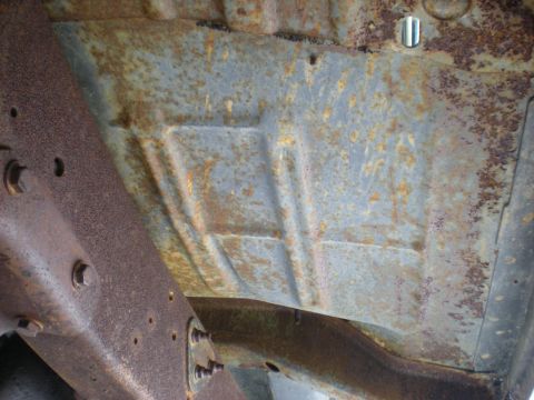 1978 Ford Bronco - The underbody of a 1978 Ford Bronco reveals significant rust and the vehicle's structural components.