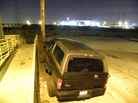 1995 Ford Bronco - A black Ford Bronco with a camper shell is parked at night, seen from a rear angle.
