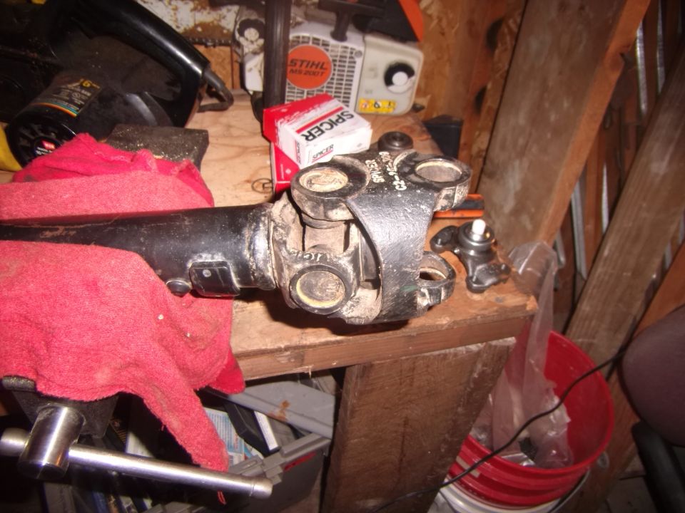 driveshaft with u-joint and a box of Spicer parts on a workbench