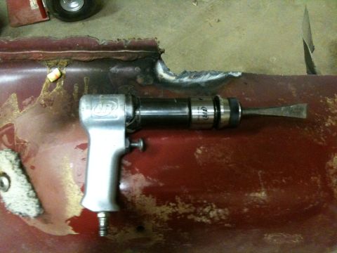 1993 Ford Bronco - Air hammer tool positioned on a section of damaged, rusty metal panel.