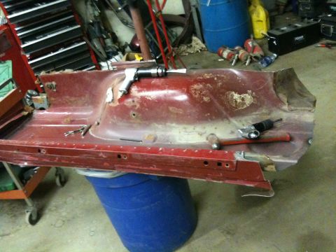 1993 Ford Bronco - A heavily rusted red metal panel, likely a car part, is shown with various tools on its surface.