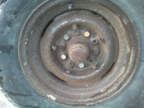 1985 Ford F-150 - Close-up view of a heavily rusted wheel hub and tire, showing wear and tear.