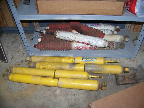 2001 Dodge 1500 - Multiple shock absorbers, some labeled Skyjacker and Monroe, are stored on a shelf and the floor.