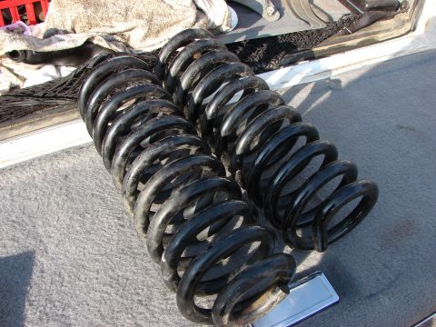 1995 Ford Bronco - Two black coil springs, likely for a vehicle lift kit, are shown resting on a carpeted surface.
