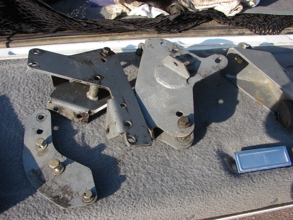several metal brackets and bolts laid out on a carpeted surface