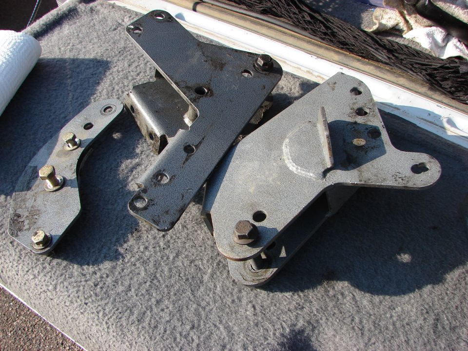 Three metal lift kit components on gray carpet