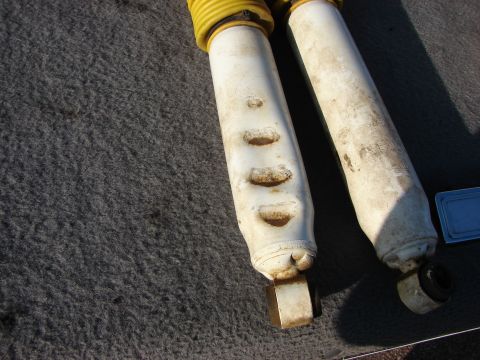1995 Ford Bronco - Close-up of two shock absorbers with yellow dust boots, likely for sale.