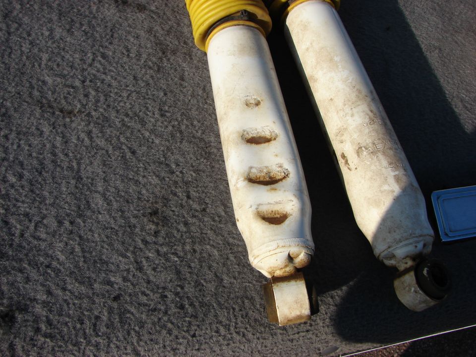 two white shock absorbers with yellow dust boots