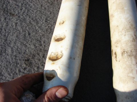 1995 Ford Bronco - Close-up of two used shock absorbers, one being held by a hand.