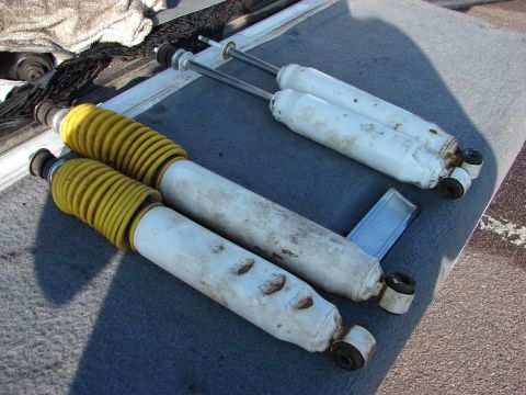 1995 Ford Bronco - Four shock absorbers, two with yellow coil springs, are displayed, likely for sale as a lift kit.