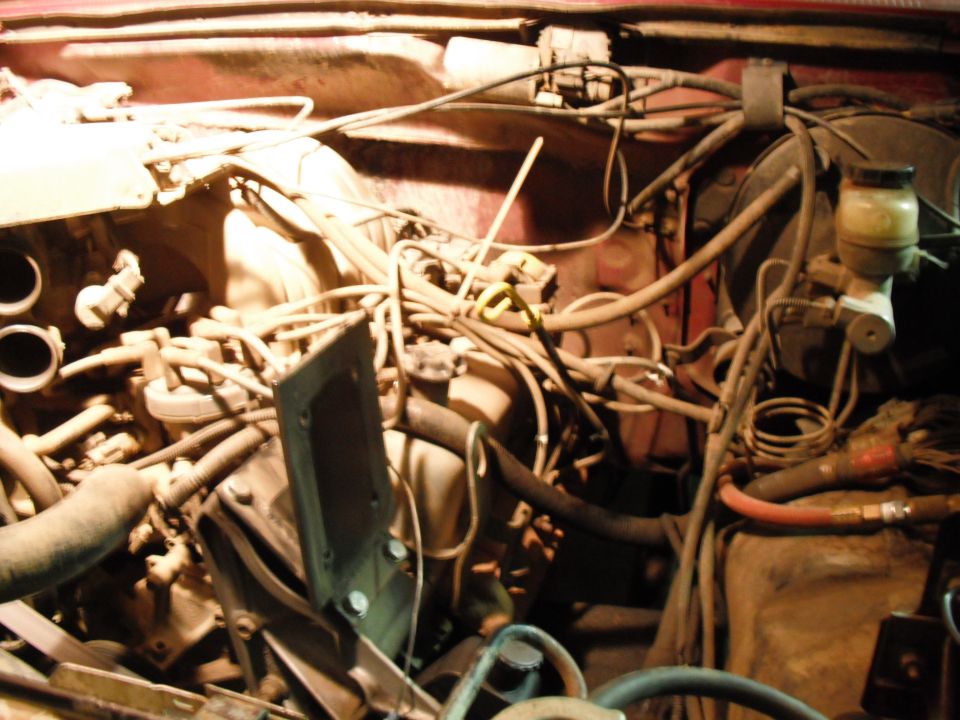 Engine bay detail showing brake fluid reservoir and numerous hoses and wires