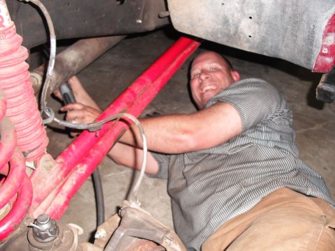 1991 Ford Bronco - Man works on vehicle suspension components, possibly a custom Y-pipe modification.