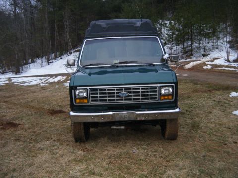 1981 Ford E350 - This van has a prominent grille and a rooftop cargo carrier, suggesting it's a model from the early 1980s.