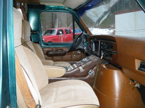 1981 Ford E350 - The interior of a van shows custom upholstery and a dashboard, with a red pickup truck seen outside.