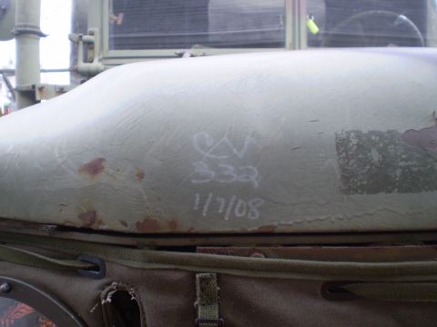 2005 Ford Excursion - Chalk markings and rust are visible on the hood of an olive drab military truck.