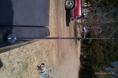 2000 Mercury Grand Marquis - A car antenna is shown extending from a dark surface, with a red truck partially visible in the background.