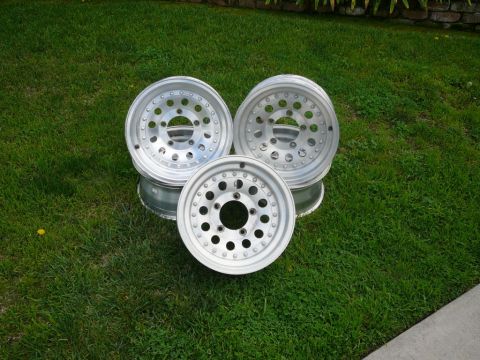 1988 Ford Bronco - Three aluminum alloy wheels are displayed on a grassy lawn.
