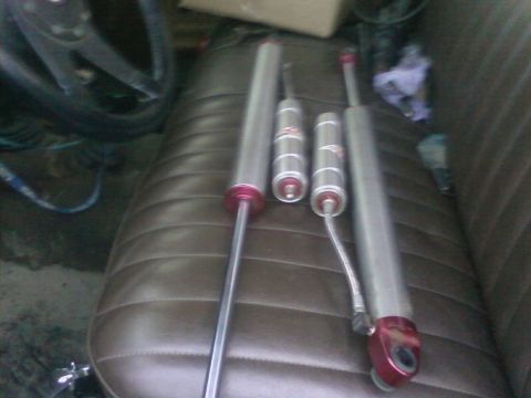 1976 Ford F-250 - Four shock absorbers are placed on a bench seat. Visible text includes 'SUPERMOTORS'.