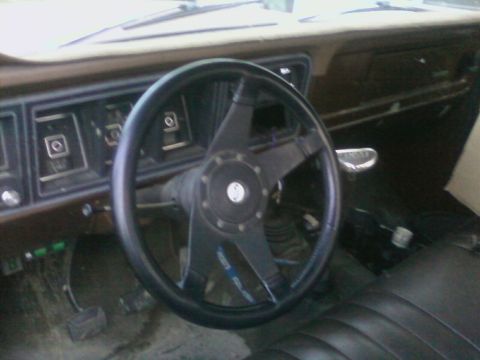 1976 Ford F-250 - The interior of a truck, a custom steering wheel and worn seats.