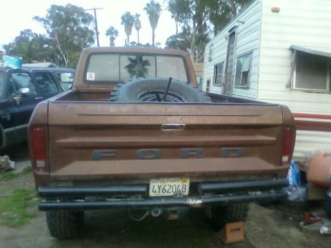 1976 Ford F-250 - Rear view of a brown 1976 Ford F-250 pickup truck, the Ford tailgate lettering and a spare tire in the bed.