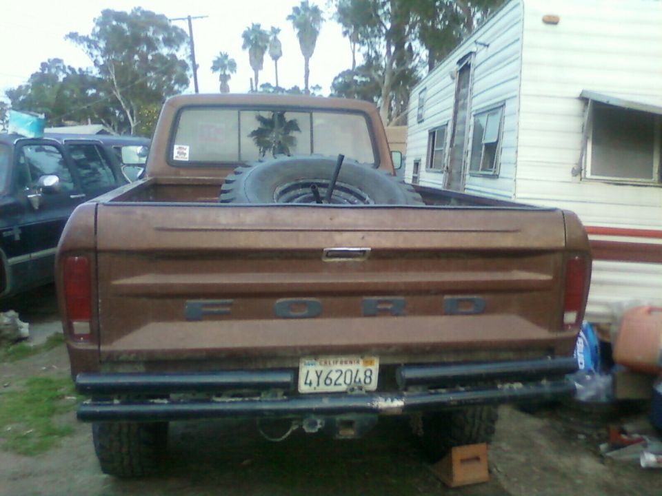 Brown 1976 Ford F-250 pickup truck rear view with spare tire in bed