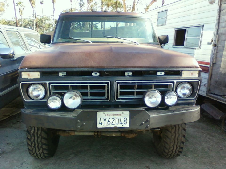 Front view of a 1976 Ford F-250 with a rusty brown finish and auxiliary lights
