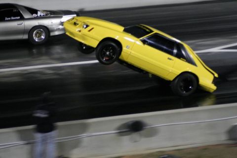 1992 Ford Mustang - A yellow fox body Mustang performs a wheelie during a drag race.