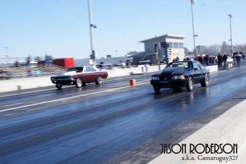 1992 Ford Mustang - A black 1992 Ford Mustang competes in a drag race, with another vehicle visible in the background.