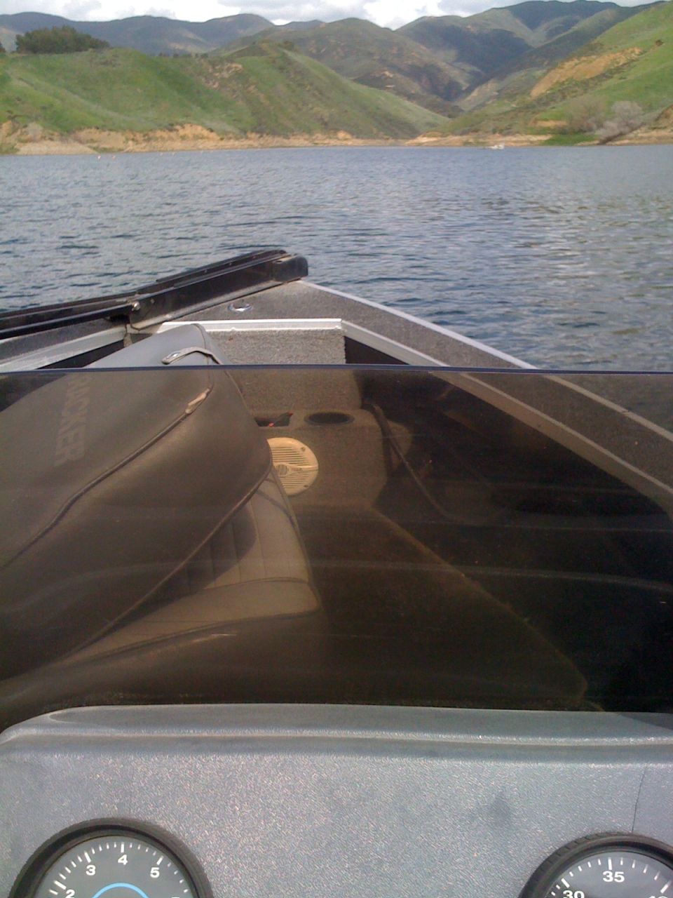 Boat interior with gauges and windshield overlooking a lake