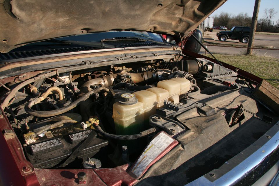 Engine bay with hood open. Black SUV visible in background