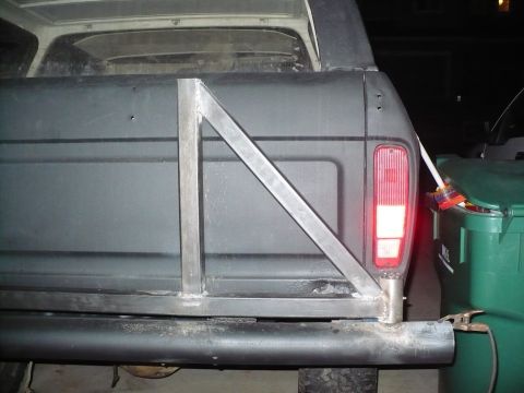 1979 Ford Bronco - The rear of a dark SUV, possibly a 1978 model, shows a custom-welded tire carrier attached to the bumper and bumper.