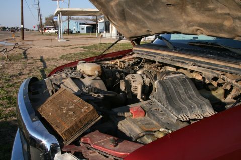 1993 Ford Bronco - The engine bay of a red truck is shown with the hood open and the air filter removed.