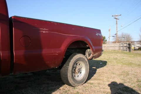 1993 Ford Bronco - Rear view of a red pickup truck bed with a 4x4 decal and visible scratches.