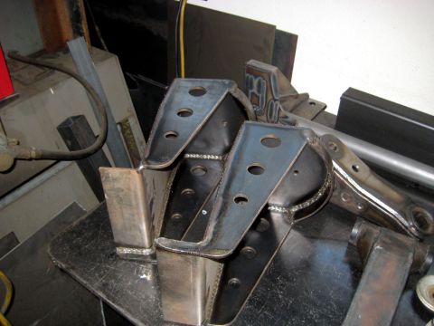 1996 Ford Bronco - Welded metal brackets, likely for automotive suspension or frame modification, are shown in a workshop setting.