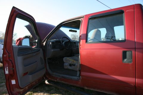 1993 Ford Bronco - The interior of a red pickup truck is visible with the driver's side door and hood open.