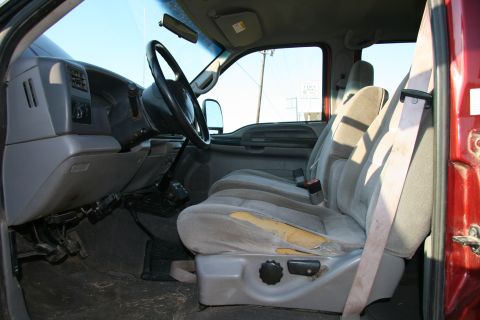 1993 Ford Bronco - The worn interior of a red truck is visible, including the dashboard and seats.